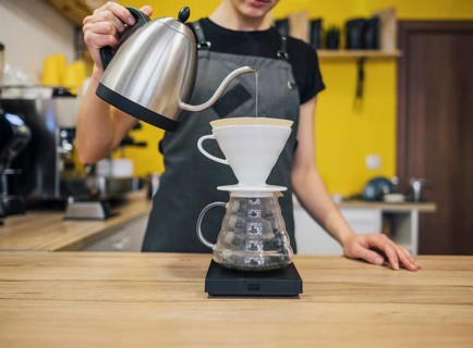 Front view female barista pouring hot water coffee filter