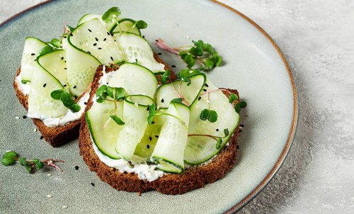 Breakfast, cereal bread sandwiches, cream cheese, sliced cucumber, with micro greenery on a light