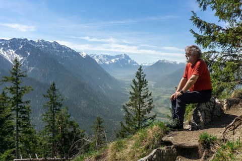 Hiker, senior citizen, 66, resting on the summit of the Osterfeuerkopf with a view of the