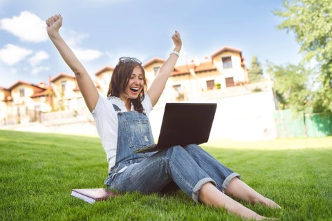 Female gets joyful emotions by talking to her friends on a conference call from notebook, she