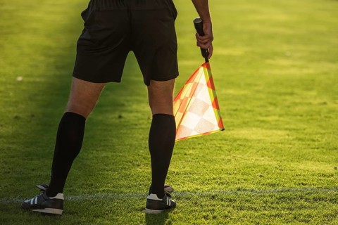 Soccer touchline referee - detail of legs and hand with the flag.
