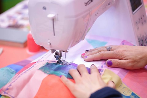 Sewing machine with hands of the seamstress at Creativeworld Frankfurt