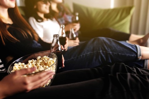 Friend group of people in 3D glasses are watching a movie, smiling, laughing. Eating and drinking