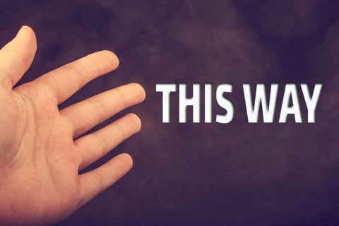 Hand making welcome gesture with THIS WAY wording