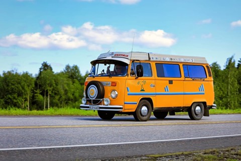 Classic yellow Volkswagen Westfalia camper van at speed on Highway 2 on a beautiful day of summer.