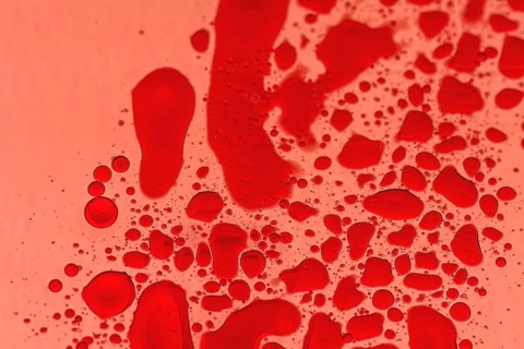 Macro of drops of red food color on cooking oil with back light through red photography gel