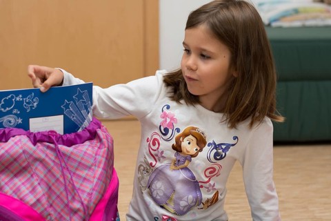 Child shows notebook from her first school bag, Austria, Europe