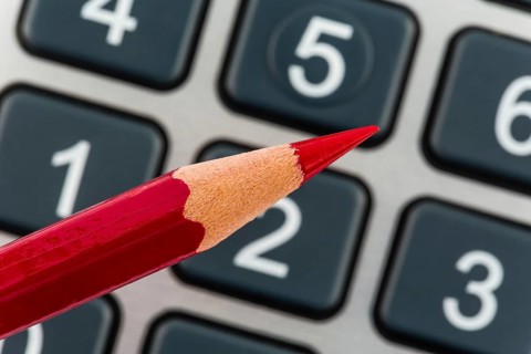 A red pen lies on a calculator. Saving on costs, expenditure and budget due to the poor economy