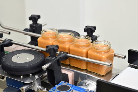 Jars of creamed honey in a packaging line at a commercial honey factory