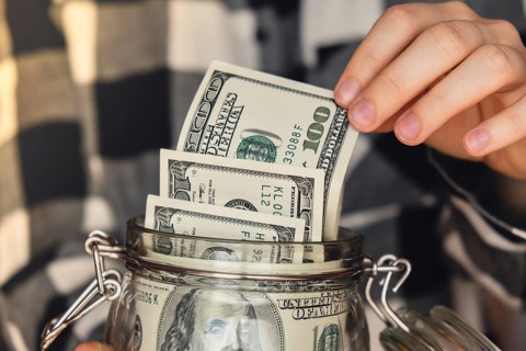 Dollar banknote saving money in glass jar. Unrecognizable woman moderate consumption and economy