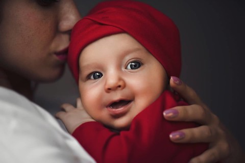 Loving Mother Cuddling Newborn Baby daughter Over Shoulder