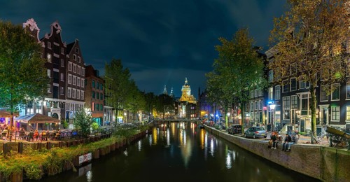 A picture of the Red Light District and the Basilica of Saint Nicholas in the distance, at night,