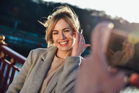 A man make a portrait of happy smiling woman standing on the bridge on sunny summer or spring day