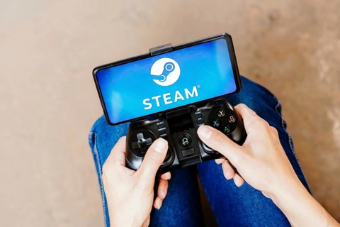 In this photo illustration, a person playing on a joystick and the Steam logo displayed on a
