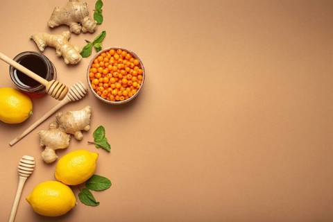 Lemons, mint, ginger, sea buckthorn berries, honey in glass jar, honey wooden dippers top view.