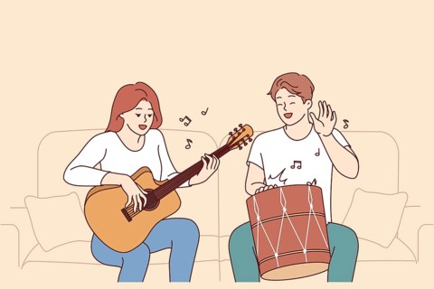 Cheerful friends man and woman playing musical instruments, sitting on sofa and using drum with