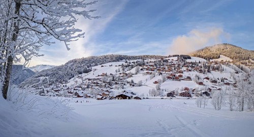 Winter panorama of snow covered La Clusaz village nestled in a hilly landscape in Annecy, France.
