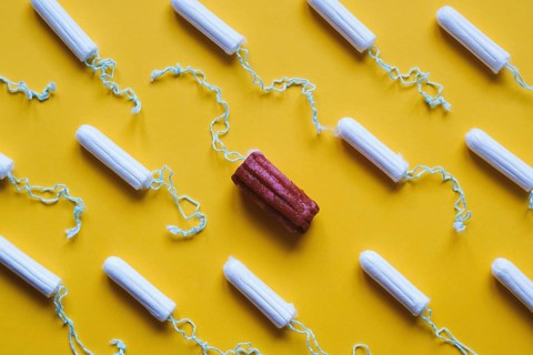 many new clean tampons and one used bloody tampon - period or menstruation flat lay concept with