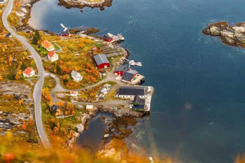 Aerial view of a small island village surrounded by a vibrant autumn landscape, mountains, rocks,