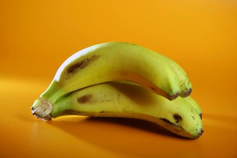 Bananas fruit cluster over orange yellow background