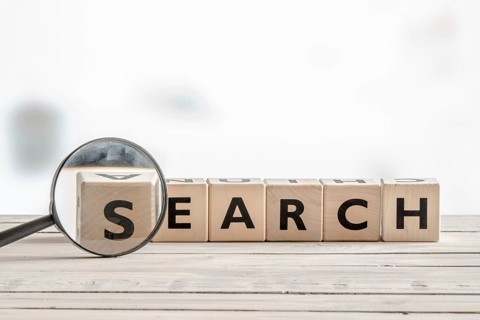 Magnifying glass with the word search on a wooden desk