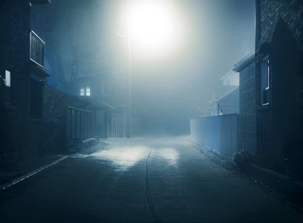 Foggy mysterious nighttime scenery of a small city street lit with a street light