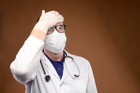 Male Caucasian doctor in white medical uniform shows face palm gesture. Chagrin and disappointment.