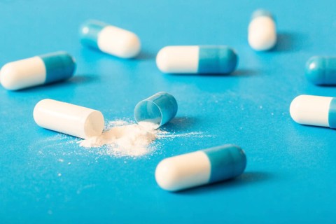 Broken white antibiotic capsule blue background