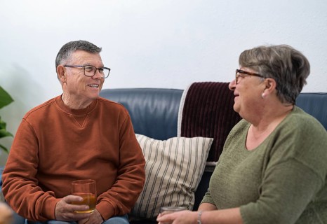Happy retired couple enjoying a relaxing afternoon at home, sharing stories and drinks on a