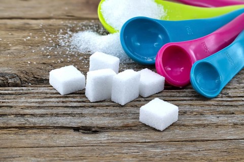 Array of sugar presentations on a wooden table, showcasing sugar cubes and granulated sugar