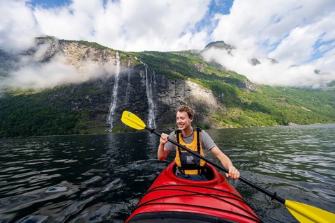 Kayak trip on the Geirangerfjord at the waterfall The Seven Sisters, Young man paddling in a kayak,