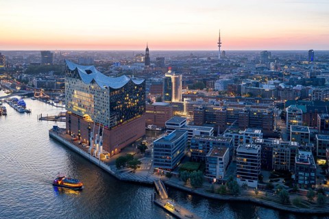 Aerial view of the Elbphilharmonie at sunset with illuminated windows and view over Hamburg,