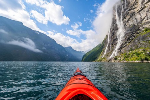 Kayak trip on the Geirangerfjord at the waterfall The Seven Sisters, tip of a red kayak in the