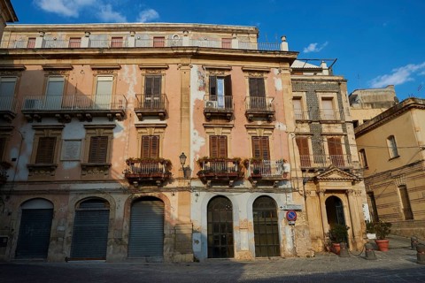 Historic building with worn balconies and shutters on a quiet street, Ortigia Island, Isola di