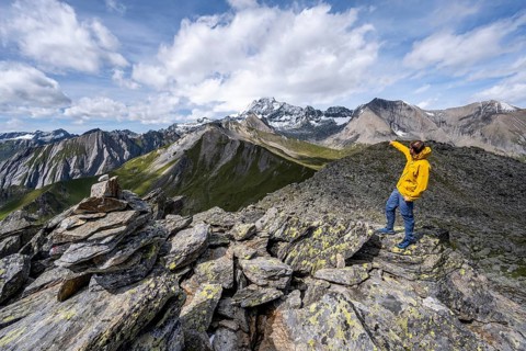 Mountaineer points into the distance, at the summit of Kastenegg, view of picturesque mountain