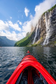 Kayak trip on the Geirangerfjord at the waterfall The Seven Sisters, tip of a red kayak in the