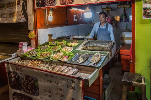 Thai street vendor offers fresh cooked seafood at the night market in downtown Chiang Rai,