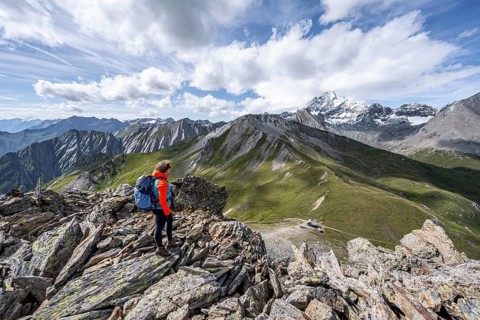 Mountaineer on the summit of Kastenegg, view of picturesque mountain landscape with snow-covered