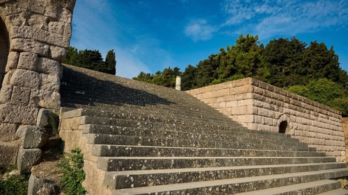 Stone staircase next to old walls, surrounded by nature and trees, open staircase to the second