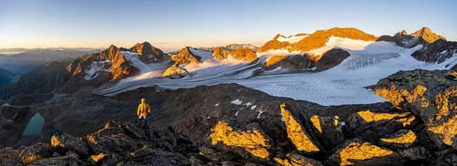 Mountaineers in front of a picturesque high mountain landscape at sunrise with alpenglow, blue