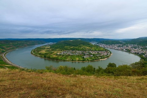 Clear picture of a river bend with neighbouring town and surrounding green hills, summer, Rhine