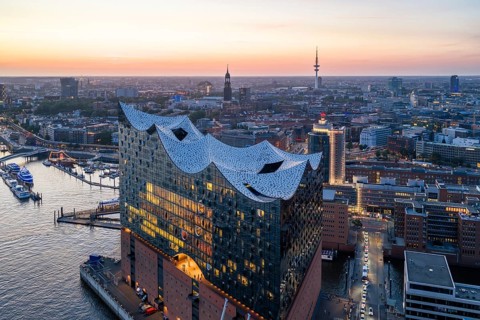 Aerial view of the Elbphilharmonie at sunset with illuminated windows and view over Hamburg,