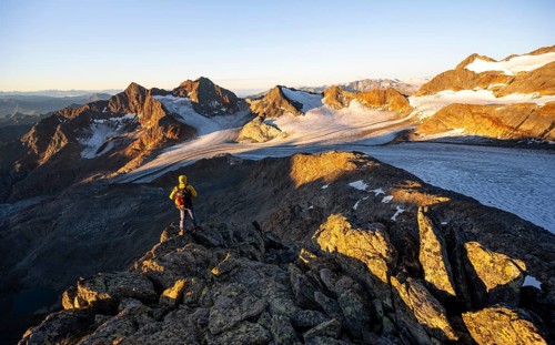 Mountaineers in front of a picturesque high mountain landscape at sunrise with alpenglow, glacier