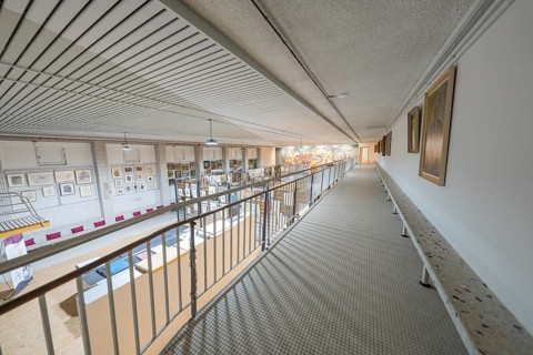 A wide corridor in a gallery with works of art on the walls and modern architectural design,