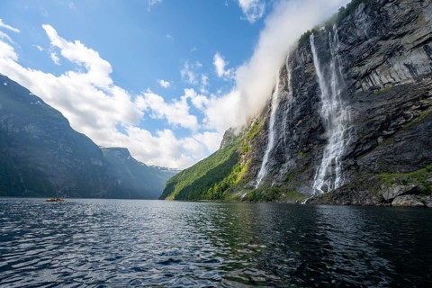 Geirangerfjord at the waterfall The Seven Sisters, tip of a red kayak in the fjord, atmospheric