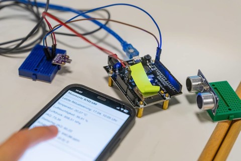Smartphone with displayed data next to an electronic setup on a table, Youth Research Centre