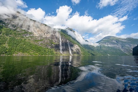 Atmospheric fjord landscape with waterfall The Seven Sisters, Geirangerfjord with reflection, Møre