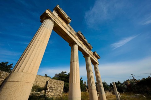 Ancient temple columns under a clear blue sky in a historical landscape, Archaeological site, Xysto