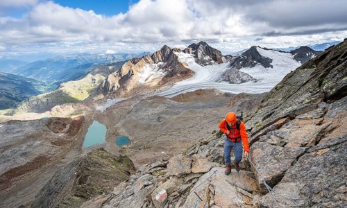 Mountaineer with helmet on a rope-insured path, in high mountain landscape, view of blue glacier