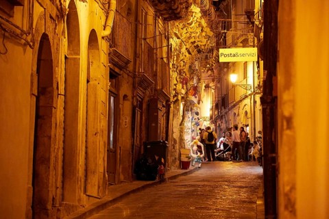 Atmospheric nocturnal alley with warm light and people in front of historic buildings under a
